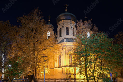 1869 Metropolitan Cathedral of Saint Mary Magdalene Orthodox church facade with Christian crosses on top of the domes illuminated at night in the Praga borough Warsaw, Poland. photo