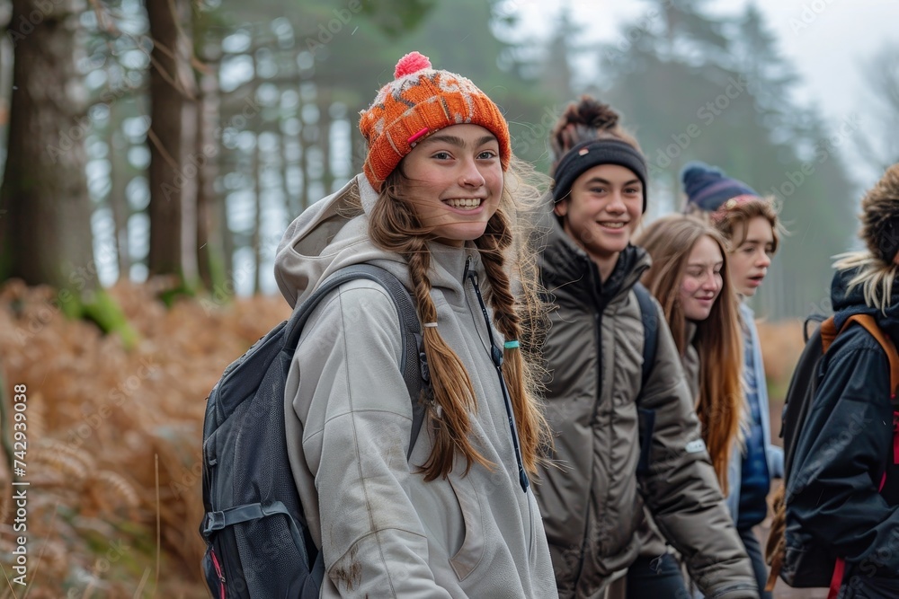 A smiling group of hikers, bundled in winter clothing and standing among the trees, enjoy the beauty of the forest on their outdoor adventure A smiling group of hikers, bundled in winter clothing and standing among the trees, enjoy the beauty of the forest on their outdoor adventure