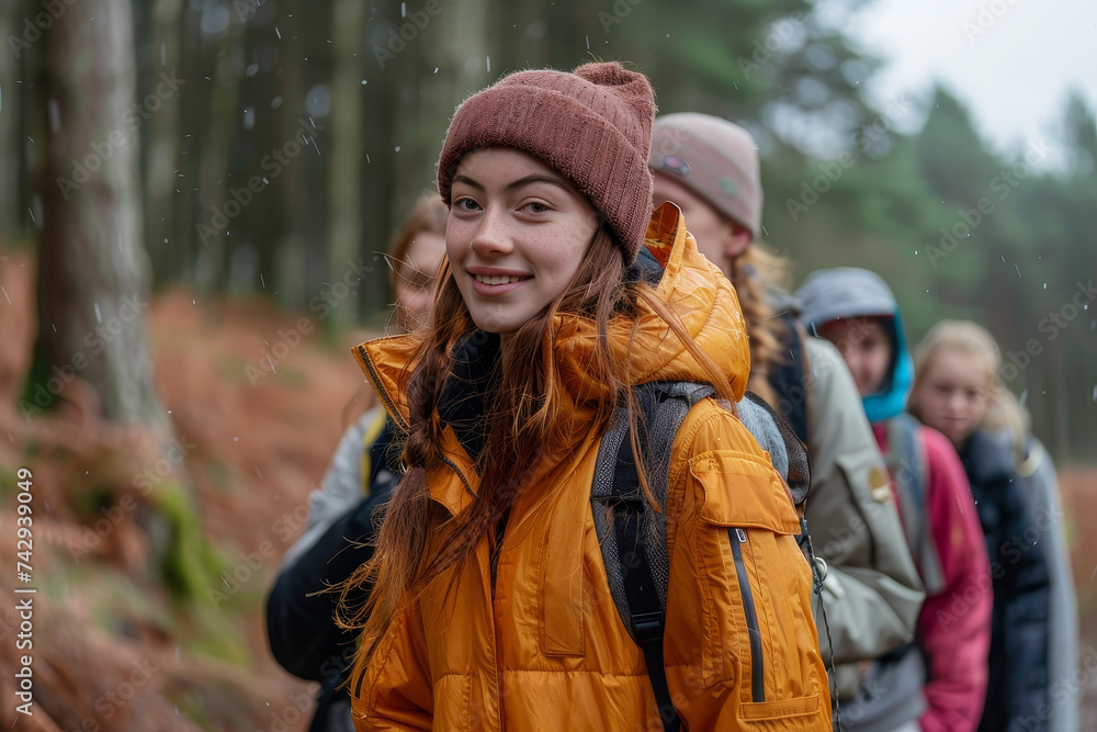 In the midst of a wintry forest, a group of hikers stand together, their smiling faces peeking out from behind warm scarves and jackets as they brave the rain and admire the towering trees against th In the midst of a wintry forest, a group of hikers stand together, their smiling faces peeking out from behind warm scarves and jackets as they brave the rain and admire the towering trees against th