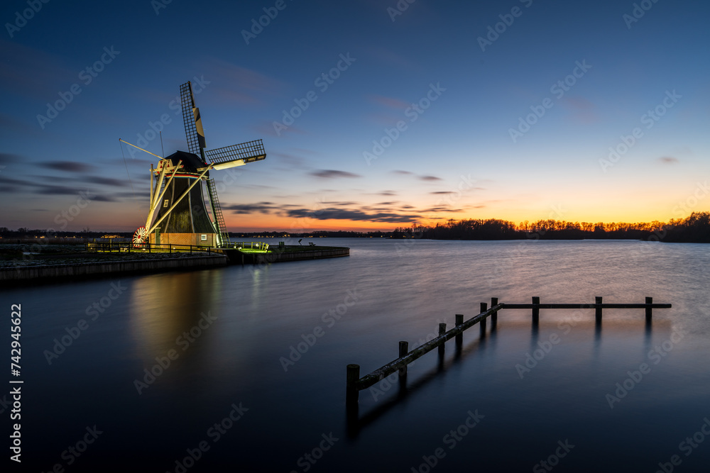 Dutch windmill at sunset along lake Paterswoldsemeer, Groningen, The Netherlands.
