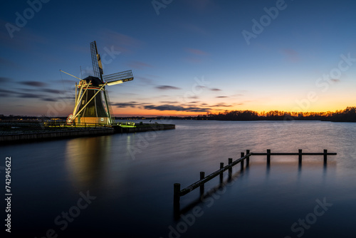 Dutch windmill at sunset along lake Paterswoldsemeer, Groningen, The Netherlands.