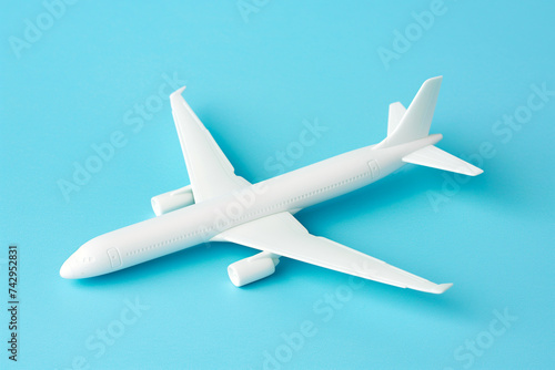 An air plane on blue background. Top view, white toy plane with copy space, minimal style. airliner, airplane, twin-engine jet aircraft. Travel and vacation concept