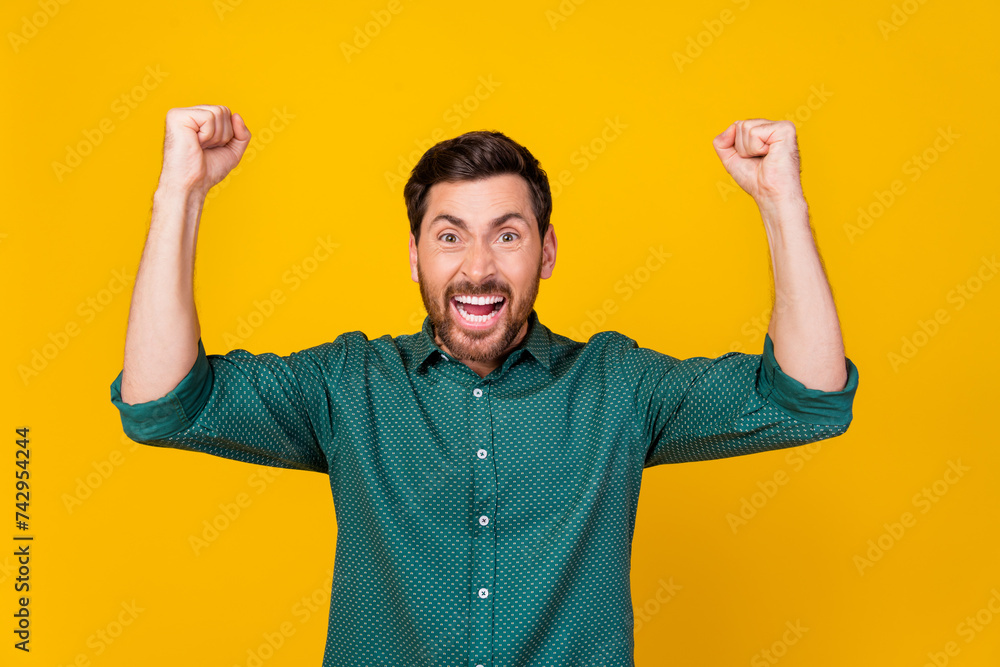 Naklejka premium Photo of crazy funny guy dressed dotted shirt raising fists up supporting football team win bet isolated on yellow color background