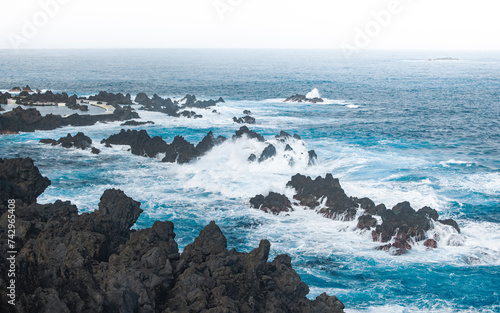 Aerial drone view of waves crashing on coastal rocks near natural pools of Porto Moniz, North-west of Madeira island, Portugal photo