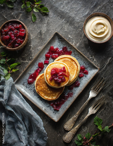 Leckere Pancakes mit frischem Rhabarberkompott und cremiger Vanillesauce Ein süßer Genuss auf vintage gestaltetem Geschirr photo