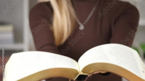 A woman's hand holds a book. A mysterious book opening. Story of the book. Selective focus on paperback. Female holding bible in hands. Opening of Holy Bible, closeup