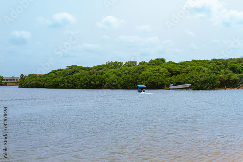 A boat alone on the ocean’s water with a forest on the back