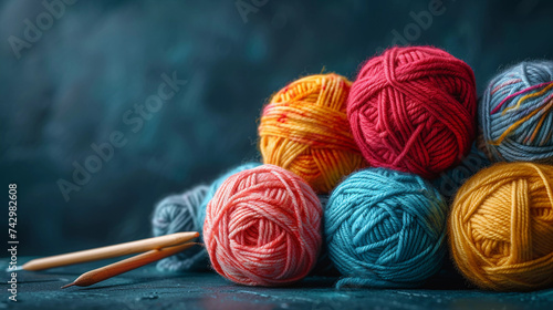 Balls of colored yarn of a dark copy space. The concept of knitting and needlework. Ball of coarse wool yarn and wooden knitting needles on dark blue background.Closeup, macro, flat lay, copy space