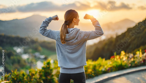 woman flexing biceps, gazing at sunrise, symbolizing motivation and empowerment photo