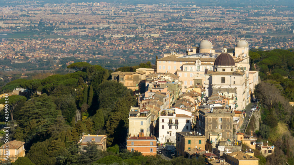 Aerial view of the Papal Palace of Castel Gandolfo. The Apostolic Palace is a complex of buildings served for centuries as a summer residence for the Pope. In background the city of Rome, Italy. 