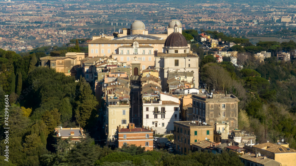 Aerial view of the Papal Palace of Castel Gandolfo. The Apostolic Palace is a complex of buildings served for centuries as a summer residence for the Pope. In background the city of Rome, Italy. 