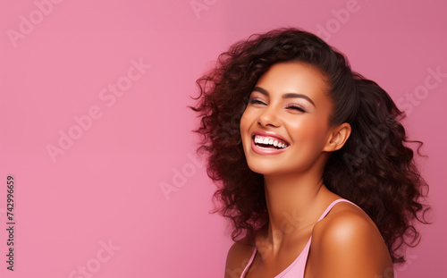 Curly girl with dark hair and perfect skin smiles and shows her white teeth on pink background, banner with space for your text