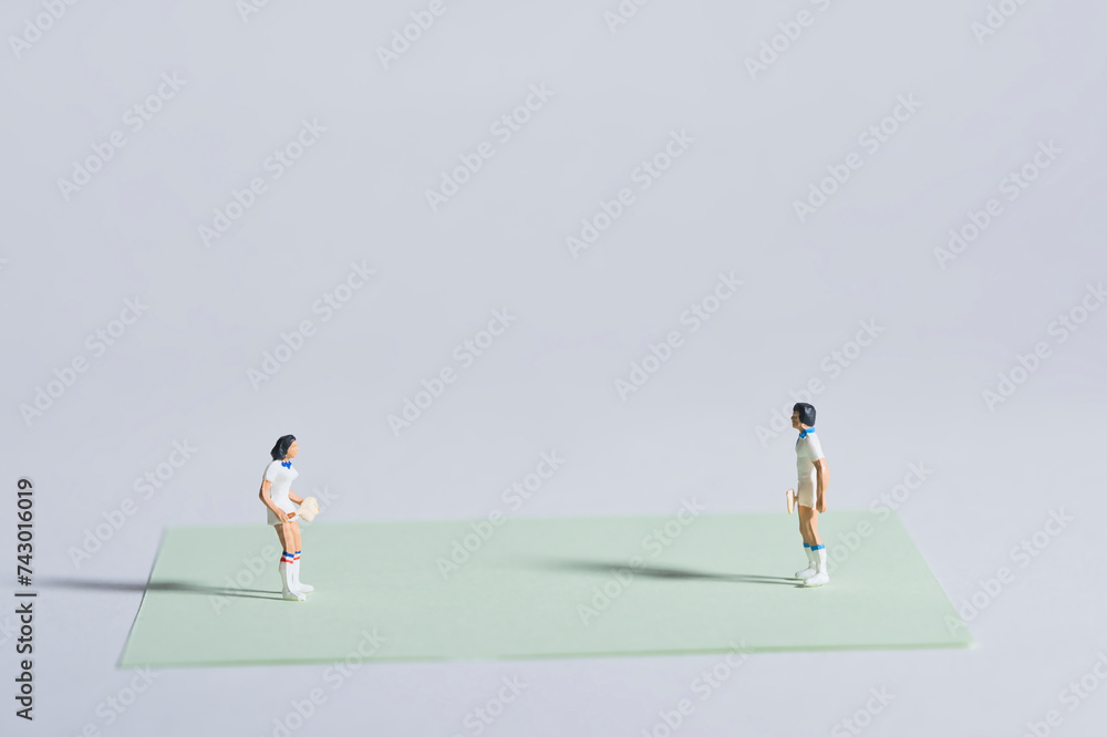 Photography of miniature people and toy figures, tennis players in action on a green sheet of paper as a tennis court