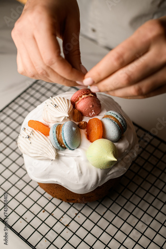 Baker decorates the Easter cake with colorful macaroons and meringue photo