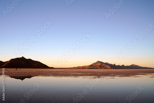 Sunset at Bonneville Salt Flats with water reflections and mountain silhouette in the background near Wendover Utah