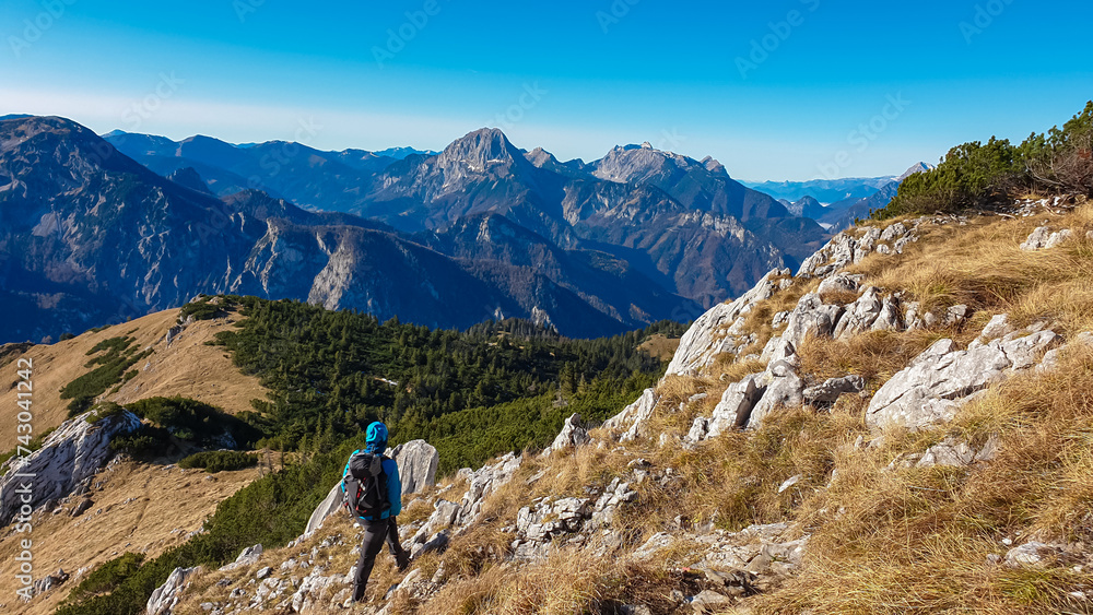 Hiker man with panoramic view of majestic mountain peaks of Gesäuse seen from Hochblaser in Eisenerz, Ennstal Alps, Styria, Austria. Idyllic hiking trail in remote nature in summer. Wanderlust concept