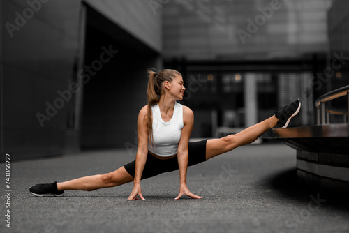 Smiling fitness woman is doing a splits stretch