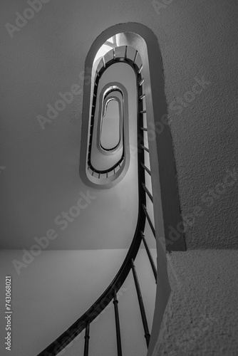 Vertical black and white photograph of an old staircase. Bottom-up view