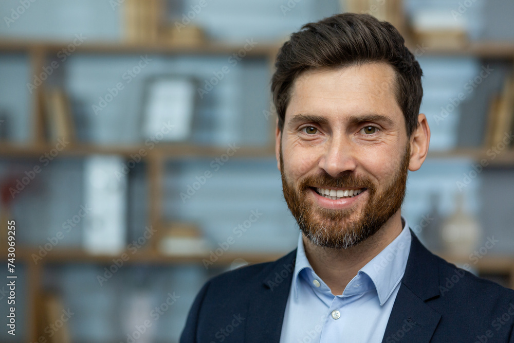 Close-up photo of a portrait of a young successful businessman, lawyer, broker standing in a suit in the office, smiling and confidently looking at the camera Close-up photo of a portrait of a young successful businessman, lawyer, broker standing in a suit in the office, smiling and confidently looking at the camera
