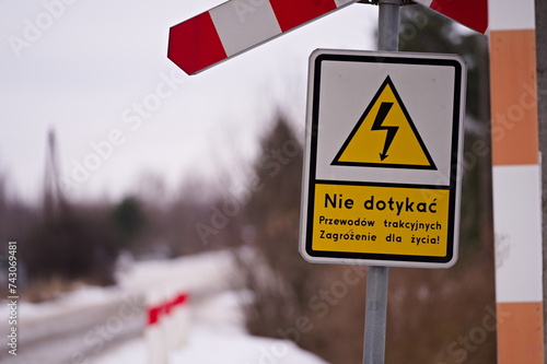 Znak "nie dotykać" pod krzyżem św. Krzysztofa na przejeździe kolejowym w zimowy dzień