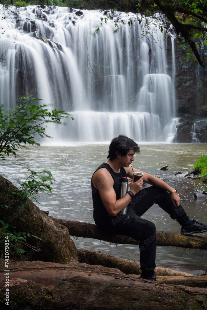 man in the waterfall drinking mate. man in the waterfall drinking mate.