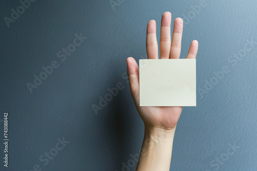Hand holding blank card, representing the anonymity of a plagiarist, gray background photo