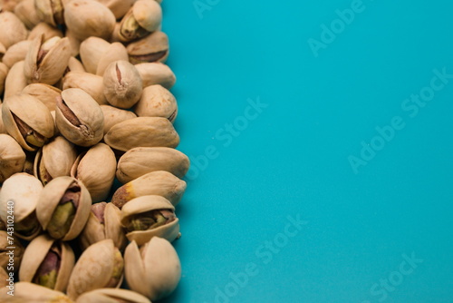 Pistachio nuts on blue background, top view with copy space