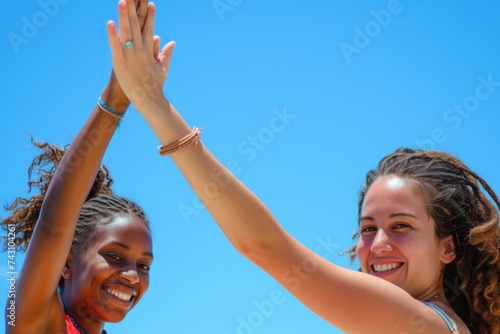 Exuberant Women High-Fiving Against a Clear Blue Sky