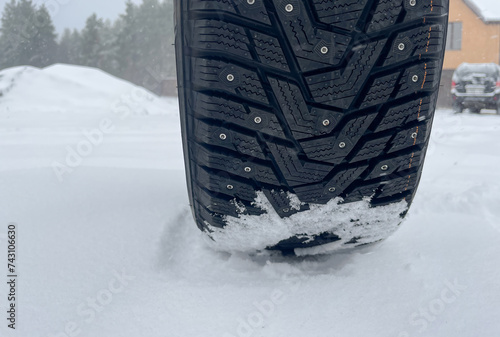 Winter tire with studs on snow, closeup © pridannikov
