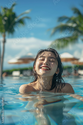 Asian woman playing in the resort swimming pool. © S photographer