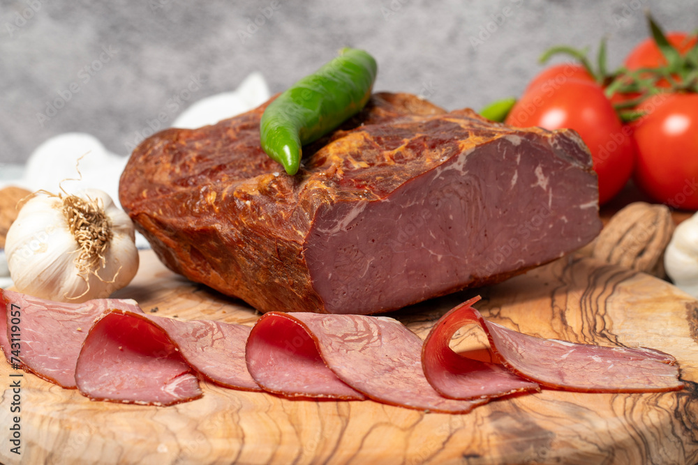 Smoked cold beef sirloin and slices on cutting board. Cold roastbeef slices on gray background. Close up Smoked cold beef sirloin and slices on cutting board. Cold roastbeef slices on gray background. Close up