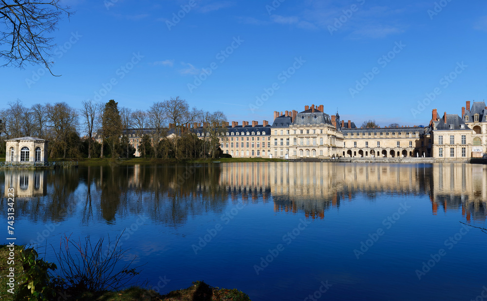 Beautiful Medieval landmark - royal hunting castle Fontainbleau with reflection in water of pond.