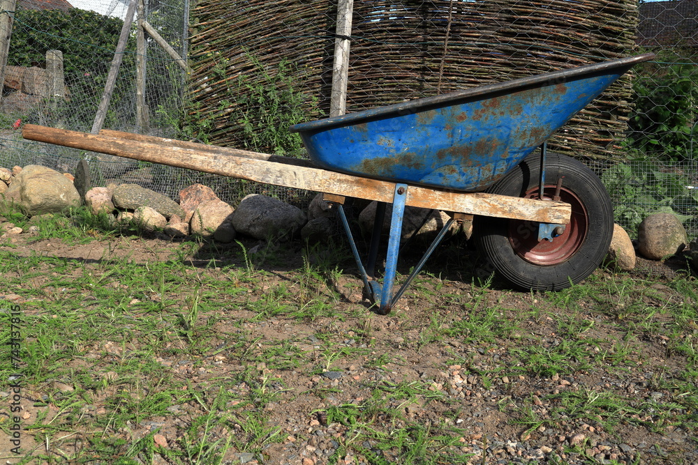 One old worn wheelbarrow. Summer day. Concept photo. One old worn wheelbarrow. Summer day. Concept photo.
