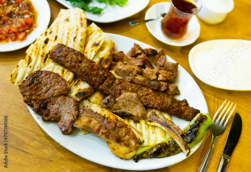 Turkish red meat plate served on dining table with flatbread and refreshments. photo