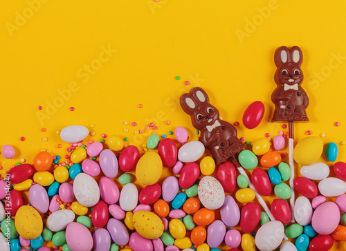 Delicious Easter holiday chocolate bunnies, eggs and sweets on yellow background. Top view, flat lay with free space for text © svittlana
