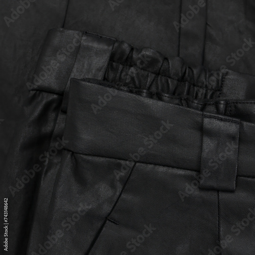 Detail of a black waxed trouser belt with loop and pocket