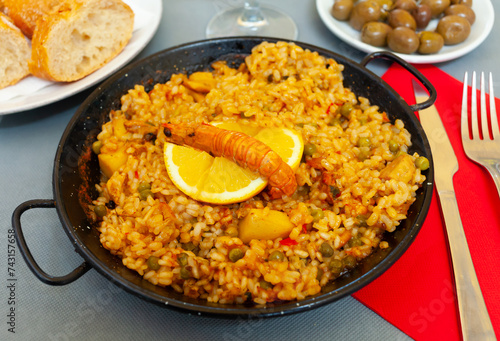 Freshly made paella with assorted seafoods served in iron frying pan with slice of lemon