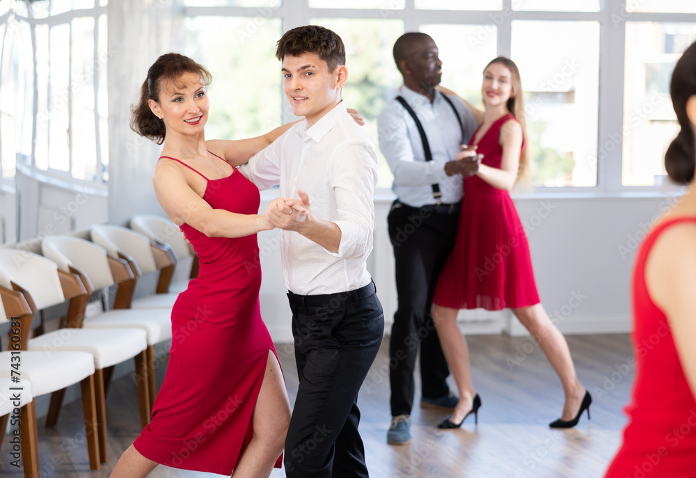 Young man and adult woman dance couple tango dance in studio