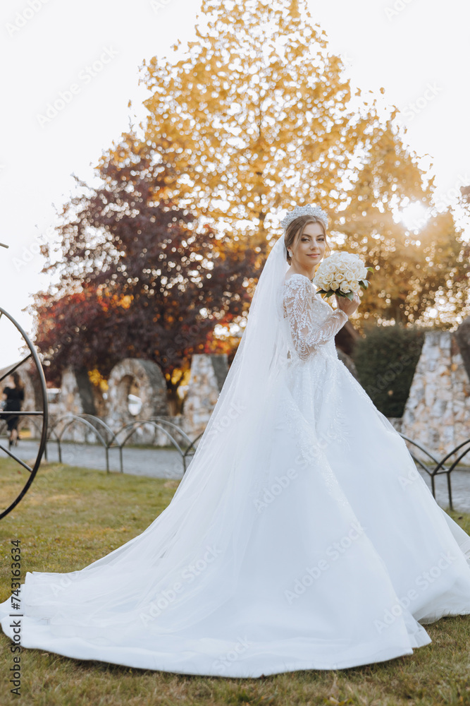Wedding photo. A brunette bride in a lacy voluminous dress, holding a bouquet and walking in the garden, smiling sincerely. Gorgeous hair and makeup. Fashion and style. Celebration. Wedding photo. A brunette bride in a lacy voluminous dress, holding a bouquet and walking in the garden, smiling sincerely. Gorgeous hair and makeup. Fashion and style. Celebration.