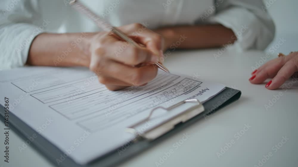 Closeup hands writing application papers on desk. Patient signing insurance form Closeup hands writing application papers on desk. Patient signing insurance form