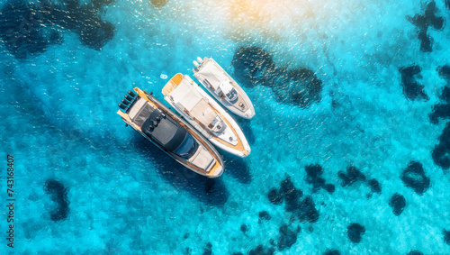 Aerial view of luxury yachts and boats on blue sea at sunset in summer. Travel in Sardinia, Italy. Drone view from above of speed boats, yachts, sea lagoon, transparent azure water. Seascape. Seaside © den-belitsky