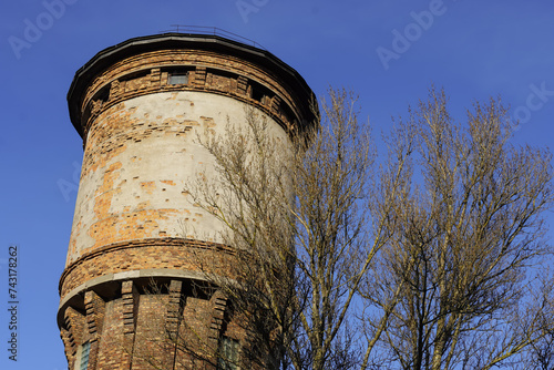 Looking up to limestone tower towards blue sky. Tree branches on the right. Tallinn, Estonia, Europe. February 2024 photo