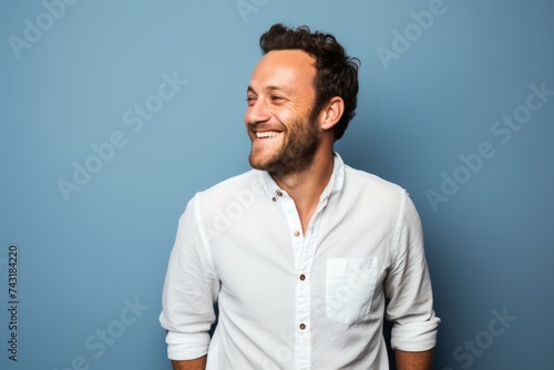 Handsome man with beard laughing and looking to the side on blue background