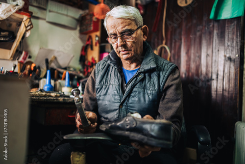 Wallpaper Mural A senior artisan sitting at his shoemaker shop and fixing shoes. Torontodigital.ca
