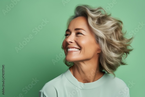Portrait of a beautiful senior woman with wavy hair on a green background © Igor