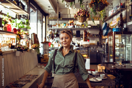 Smiling portrait of a middle aged caucasian female waitress or owner of a small family restaurant in the city photo