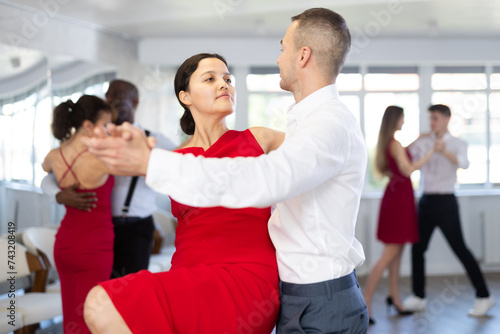 Energy man and Asian woman are dancing tango in couple during lesson at studio. Leisure activities and physical activity for positive people.