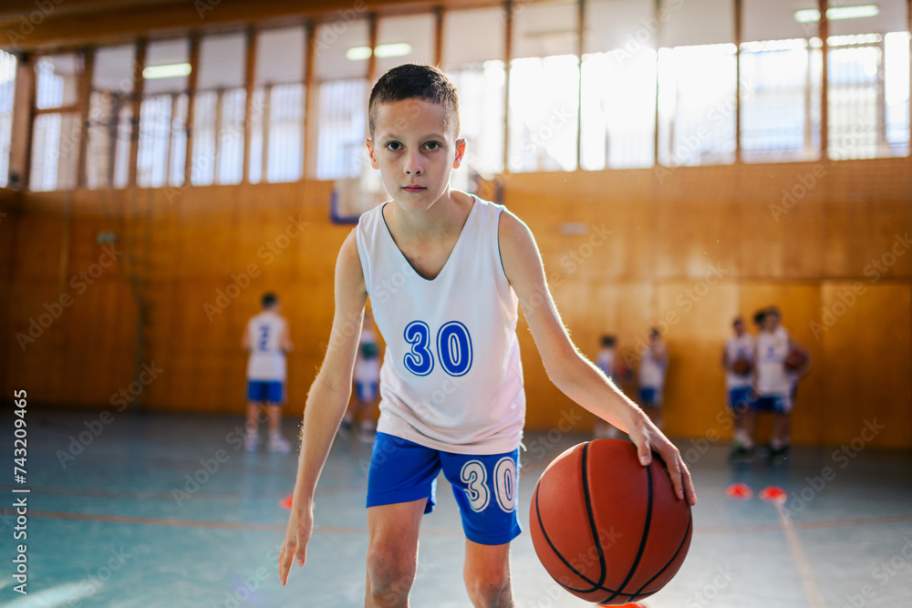 A young active athlete is dribbling a basketball on training at court. A young active athlete is dribbling a basketball on training at court.