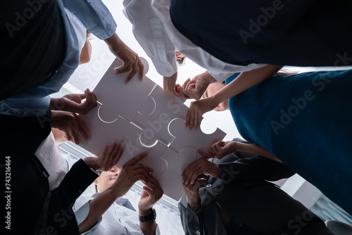 Canvas Print Below view of diverse corporate officer workers collaborate in office connecting puzzle pieces as partnership and teamwork concept