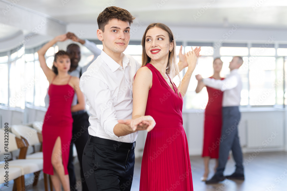Fototapeta premium Energy man and young woman are dancing classic version of waltz in couple during lesson at studio. Leisure activities and physical activity for positive people.